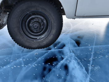 Вид на колесо авто и прозрачный лед Байкала